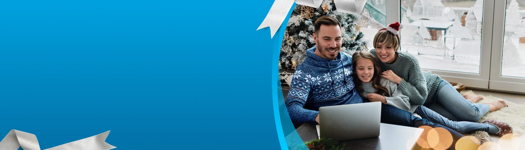 Happy family wearing holiday sweaters looking at laptop